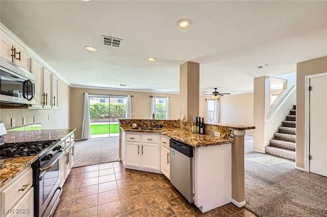 7382 Elbridge Way, Las Vegas, NV 89113 - kitchen featuring appliances with stainless steel finishes, a sink, dark carpet, dark stone countertops, and white cabinets