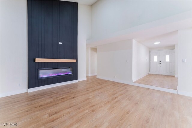 3409 El Cortez Ave, Las Vegas, NV 89102 - unfurnished living room featuring wood finished floors, a large fireplace, baseboards, and a high ceiling