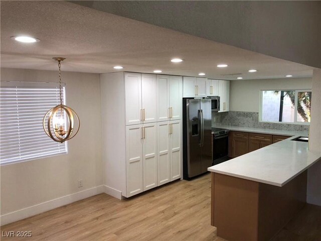 3409 El Cortez Ave, Las Vegas, NV 89102 - kitchen featuring appliances with stainless steel finishes, light wood-style floors, a chandelier, a peninsula, and light countertops