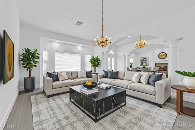 4418 Desert Bloom Ct, Las Vegas, NV 89129 - living room featuring decorative columns, a chandelier, light wood-type flooring, arched walkways, and recessed lighting