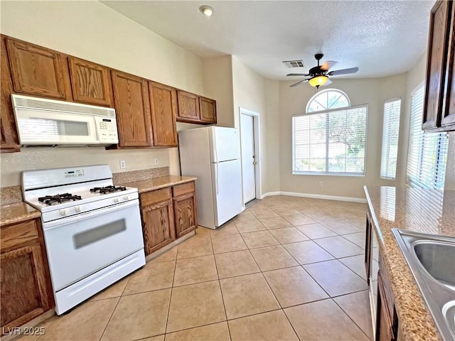 2119 Sunset Vista Ave, Henderson, NV 89052 - kitchen featuring white appliances, brown cabinetry, ceiling fan, a sink, and light tile patterned floors