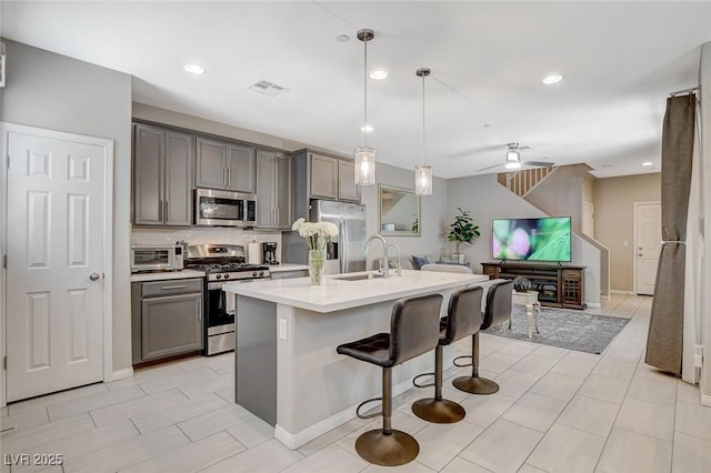 4537 Cloudrest Peak St, North Las Vegas, NV 89031 - kitchen with stainless steel appliances, gray cabinetry, a sink, open floor plan, and a breakfast bar area