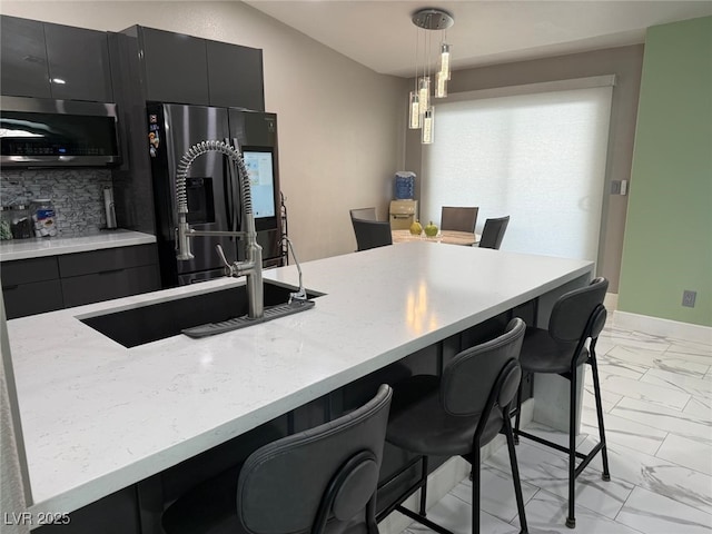 6248 Sapporo Cir, Las Vegas, NV 89110 - kitchen featuring light marble finish flooring, stainless steel microwave, a breakfast bar area, fridge with ice dispenser, and decorative backsplash