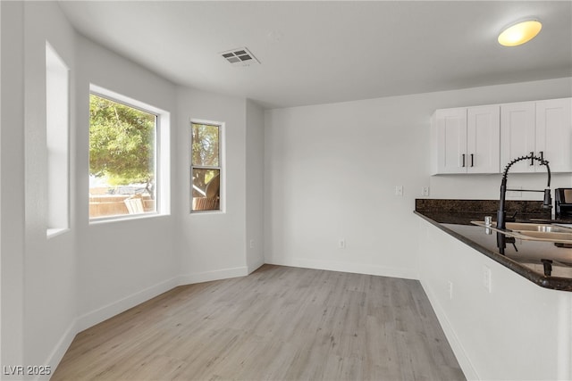 6117 Daisy Lee Ave, Las Vegas, NV 89108 - kitchen featuring light wood finished floors, a sink, white cabinets, and baseboards