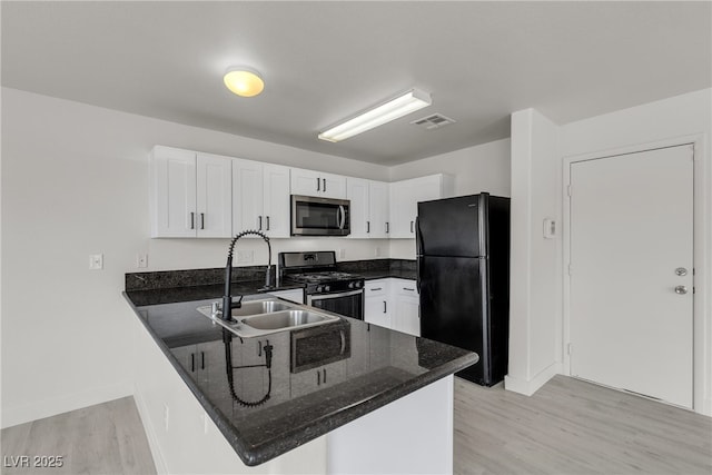 6117 Daisy Lee Ave, Las Vegas, NV 89108 - kitchen featuring freestanding refrigerator, range with gas cooktop, stainless steel microwave, a peninsula, and white cabinets