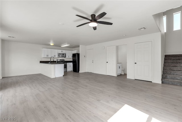 6117 Daisy Lee Ave, Las Vegas, NV 89108 - unfurnished living room featuring ceiling fan, light wood-style flooring, stairs, and a sink