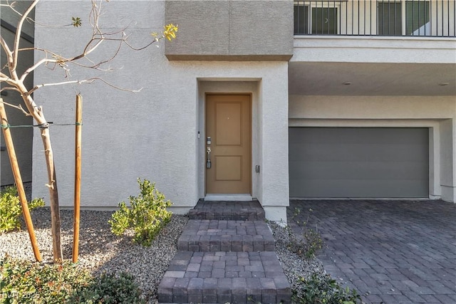 6952 Crescent Gold St, North Las Vegas, NV 89086 - view of exterior entry featuring a garage, stucco siding, and decorative driveway
