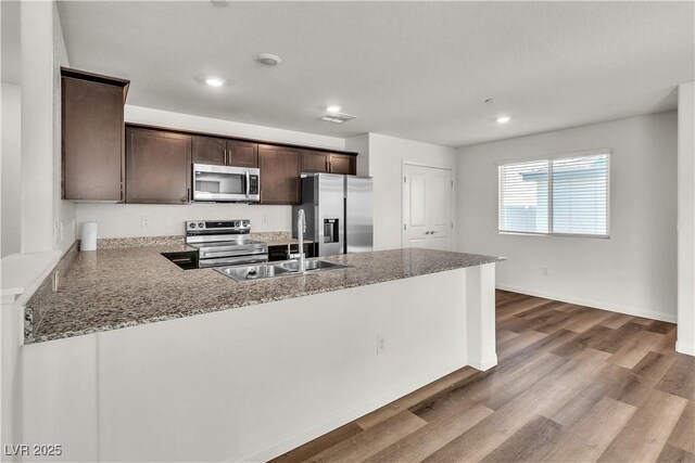 6952 Crescent Gold St, North Las Vegas, NV 89086 - kitchen with appliances with stainless steel finishes, dark brown cabinets, a sink, recessed lighting, and a peninsula