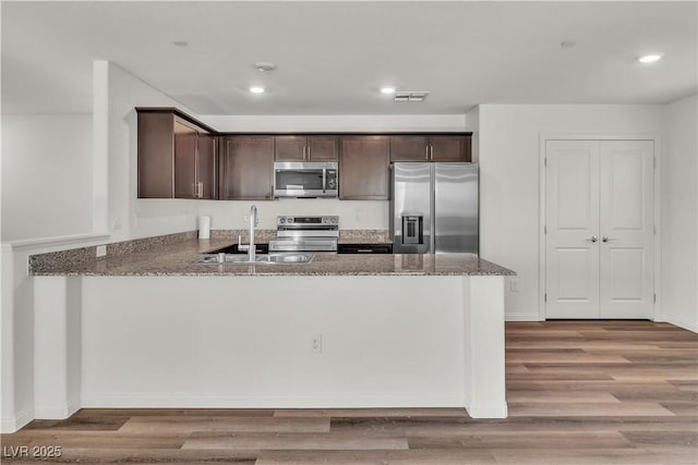 6952 Crescent Gold St, North Las Vegas, NV 89086 - kitchen featuring stainless steel appliances, dark brown cabinetry, a sink, stone countertops, and a peninsula