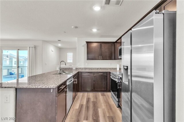 6952 Crescent Gold St, North Las Vegas, NV 89086 - kitchen featuring appliances with stainless steel finishes, a sink, light wood finished floors, dark brown cabinets, and a peninsula