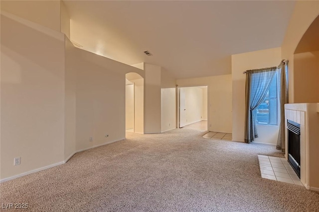 3426 Side Saddle Ct, North Las Vegas, NV 89032 - spare room with light colored carpet, arched walkways, a tiled fireplace, and baseboards