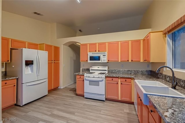 3426 Side Saddle Ct, North Las Vegas, NV 89032 - kitchen featuring white appliances, a sink, arched walkways, high vaulted ceiling, and light wood-type flooring