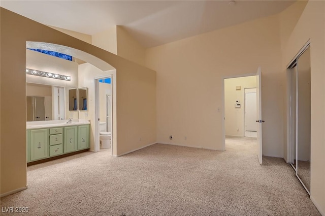 3426 Side Saddle Ct, North Las Vegas, NV 89032 - unfurnished bedroom with a sink, light carpet, arched walkways, high vaulted ceiling, and connected bathroom