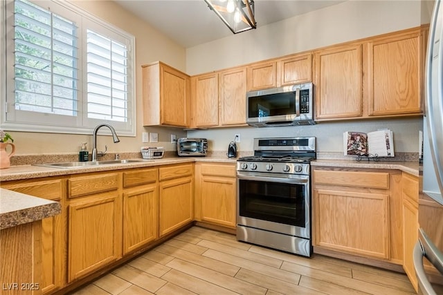 7694 Hampton Park Ln, Las Vegas, NV 89113 - kitchen featuring stainless steel appliances, a sink, light wood-style flooring, and light brown cabinetry