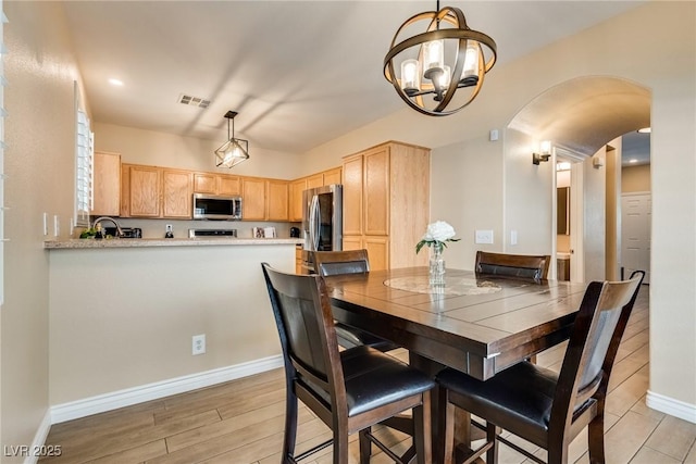7694 Hampton Park Ln, Las Vegas, NV 89113 - dining space with arched walkways, a chandelier, baseboards, and light wood-type flooring