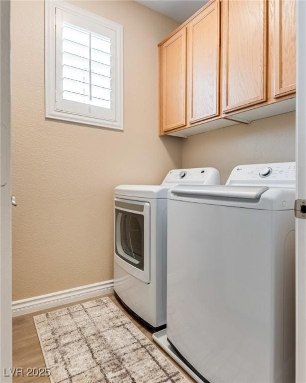 7694 Hampton Park Ln, Las Vegas, NV 89113 - washroom with washer and dryer, cabinet space, baseboards, and light wood-style flooring