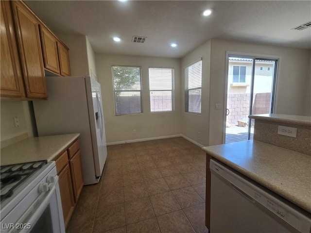 9312 Gold Dove Ct, Las Vegas, NV 89178 - kitchen with white appliances, brown cabinets, dark tile patterned flooring, recessed lighting, and light countertops