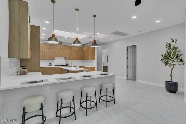 7738 Willow Cove Cir, Las Vegas, NV 89129 - kitchen with modern cabinets, light countertops, brown cabinetry, a peninsula, and a breakfast bar