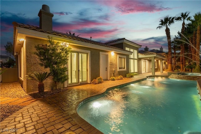 7738 Willow Cove Cir, Las Vegas, NV 89129 - back of house with a patio area, a chimney, a pool with connected hot tub, french doors, and stucco siding