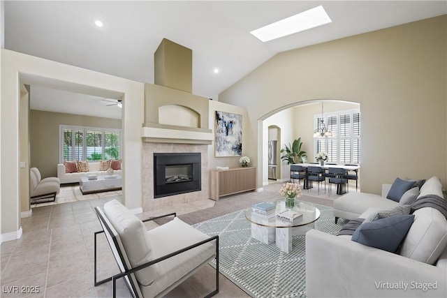 8541 Highland View Ave, Las Vegas, NV 89145 - living room featuring arched walkways, a fireplace, a ceiling fan, vaulted ceiling, and a chandelier