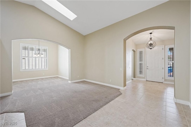8541 Highland View Ave, Las Vegas, NV 89145 - unfurnished room featuring a chandelier, lofted ceiling, arched walkways, baseboards, and light carpet