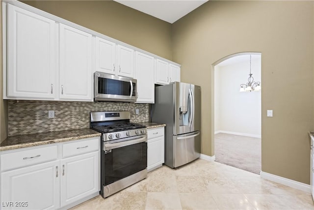 8541 Highland View Ave, Las Vegas, NV 89145 - kitchen with appliances with stainless steel finishes, a chandelier, decorative backsplash, white cabinets, and light carpet