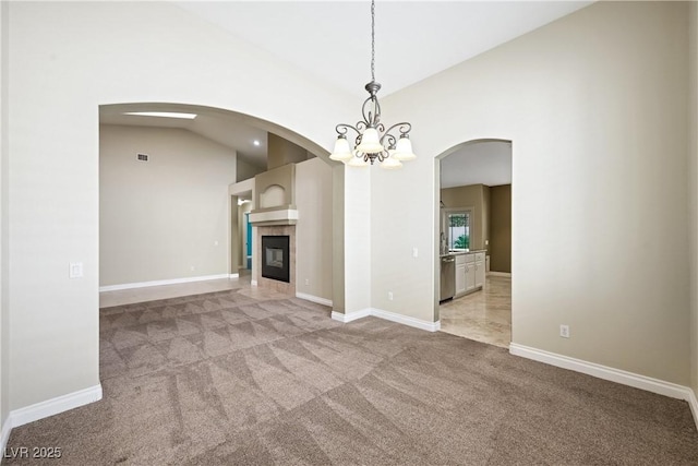8541 Highland View Ave, Las Vegas, NV 89145 - unfurnished living room featuring light colored carpet, arched walkways, vaulted ceiling, a chandelier, and baseboards