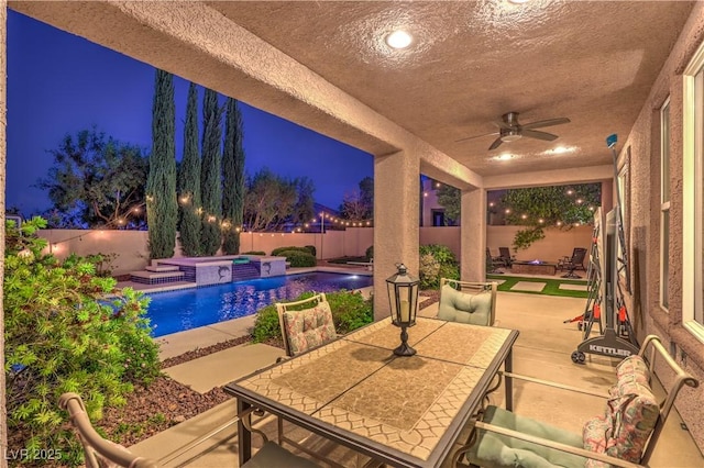 2982 Hammerwood Dr, Las Vegas, NV 89135 - patio at night featuring ceiling fan, outdoor dining space, a patio area, a fenced backyard, and a hot tub