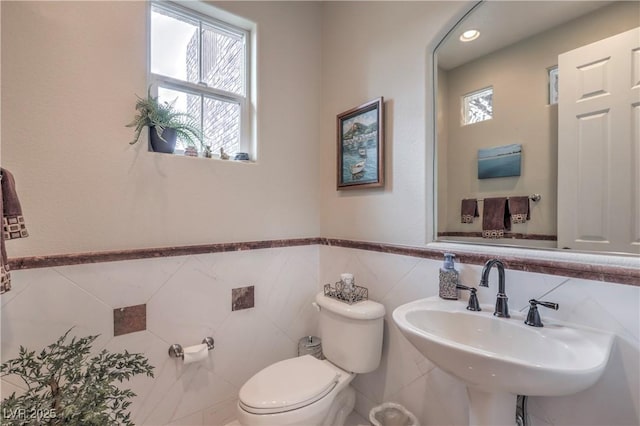 2982 Hammerwood Dr, Las Vegas, NV 89135 - bathroom featuring toilet, tile walls, a sink, and wainscoting