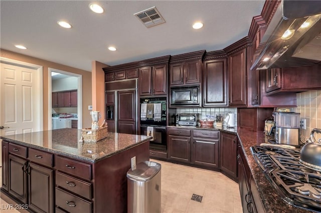 2982 Hammerwood Dr, Las Vegas, NV 89135 - kitchen featuring washer and clothes dryer, black appliances, wall chimney exhaust hood, a kitchen island, and decorative backsplash