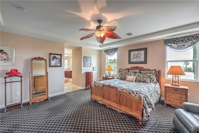 2982 Hammerwood Dr, Las Vegas, NV 89135 - bedroom featuring dark colored carpet, baseboards, ensuite bath, and a tray ceiling