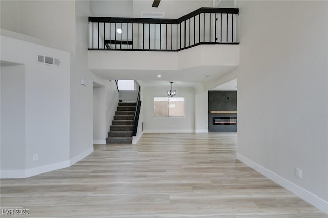 71 Sea Holly Way, Henderson, NV 89074 - unfurnished living room featuring stairway, baseboards, wood finished floors, a chandelier, and a high ceiling