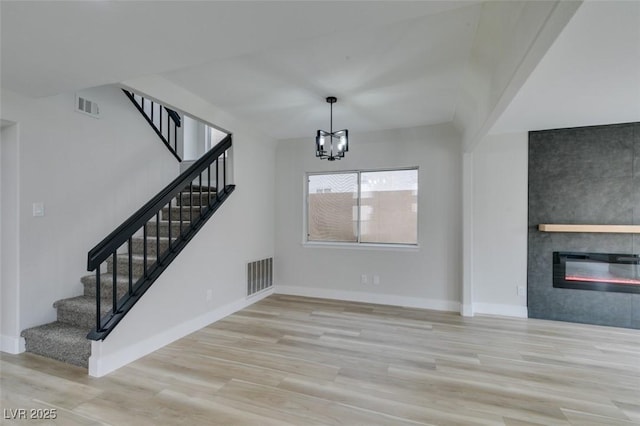 71 Sea Holly Way, Henderson, NV 89074 - unfurnished living room with wood finished floors, stairway, a chandelier, a large fireplace, and baseboards