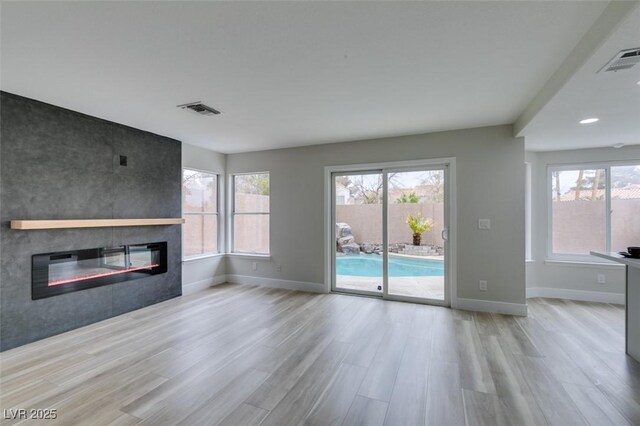 71 Sea Holly Way, Henderson, NV 89074 - unfurnished living room featuring a fireplace, wood finished floors, baseboards, and healthy amount of natural light