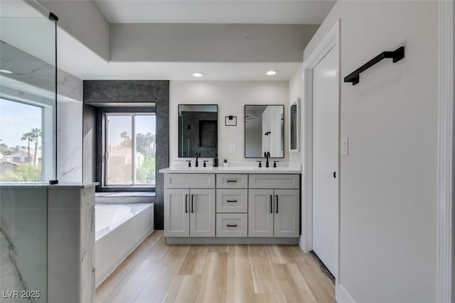 71 Sea Holly Way, Henderson, NV 89074 - bathroom featuring double vanity, a bath, recessed lighting, and wood finished floors