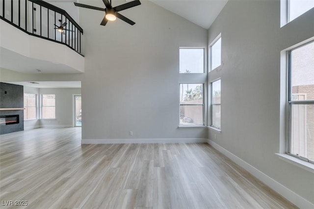 71 Sea Holly Way, Henderson, NV 89074 - unfurnished living room with high vaulted ceiling, a ceiling fan, wood finished floors, baseboards, and a fireplace