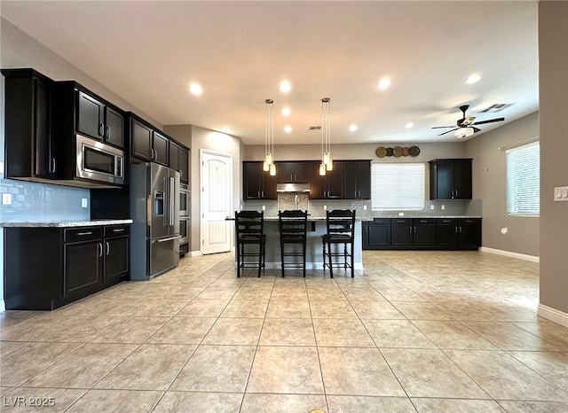 10719 Hammett Park Ave, Las Vegas, NV 89166 - kitchen with stainless steel appliances, under cabinet range hood, decorative backsplash, a breakfast bar area, and recessed lighting