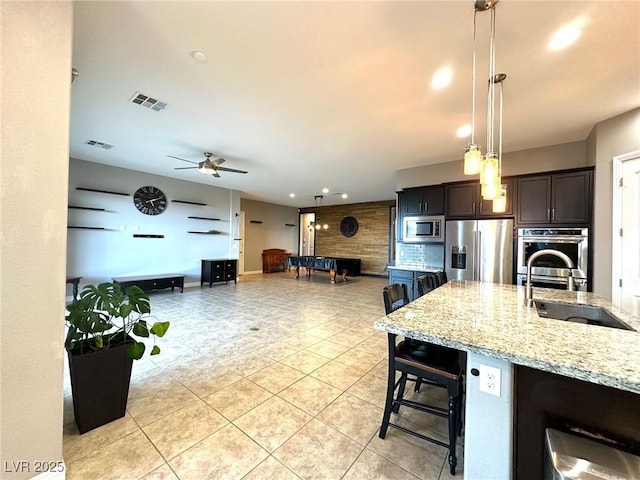 10719 Hammett Park Ave, Las Vegas, NV 89166 - kitchen with stainless steel appliances, decorative backsplash, light tile patterned floors, a ceiling fan, and light stone counters