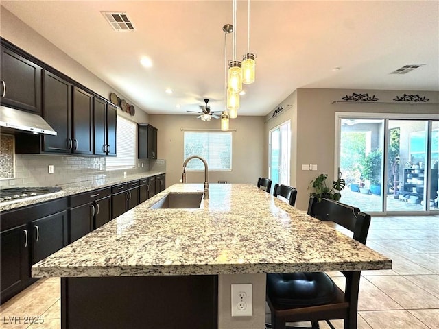 10719 Hammett Park Ave, Las Vegas, NV 89166 - kitchen with a sink, under cabinet range hood, stainless steel gas cooktop, a breakfast bar, and a ceiling fan