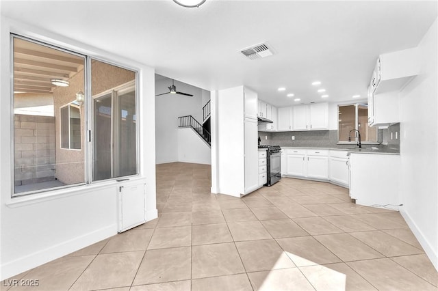 6717 Sheffield Dr, Las Vegas, NV 89108 - kitchen featuring black gas range oven, light tile patterned floors, white cabinets, tasteful backsplash, and light countertops