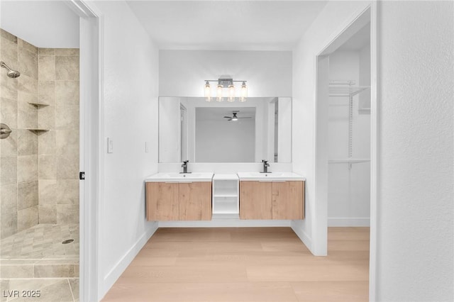 6717 Sheffield Dr, Las Vegas, NV 89108 - bathroom featuring a stall shower, double vanity, a ceiling fan, a walk in closet, and wood finished floors