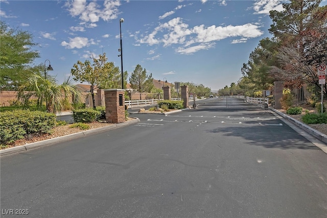 9312 Straw Hays St Unit 103, Las Vegas, NV 89178 - view of asphalt road with a gate, curbs, street lights, traffic signs, and a gated entry