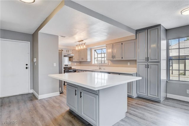 3971 Foxboro Cir, Las Vegas, NV 89121 - kitchen featuring gray cabinetry, under cabinet range hood, light countertops, and baseboards