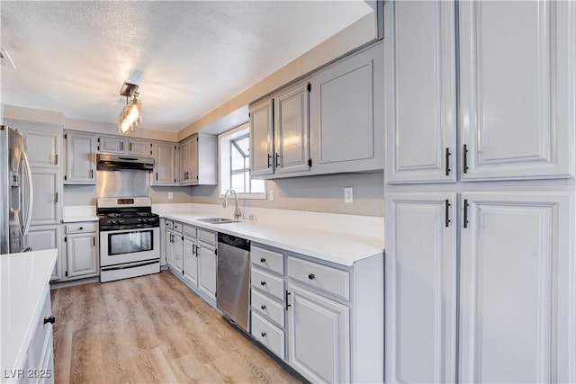 3971 Foxboro Cir, Las Vegas, NV 89121 - kitchen with stainless steel appliances, a sink, under cabinet range hood, light countertops, and light wood-style flooring