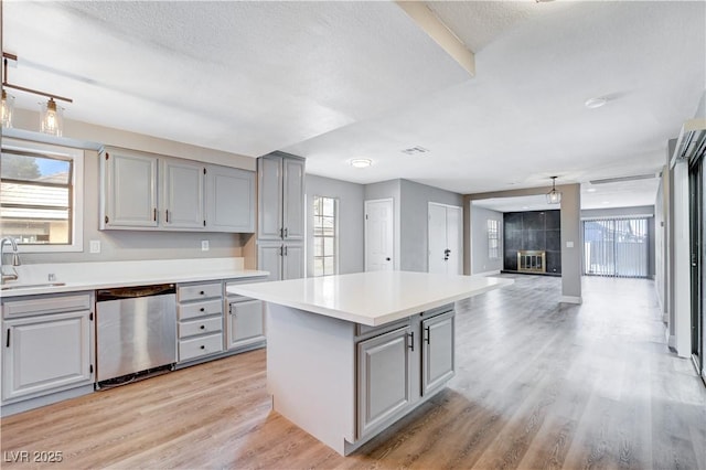 3971 Foxboro Cir, Las Vegas, NV 89121 - kitchen featuring dishwasher, gray cabinetry, a kitchen island, light wood-style floors, and light countertops