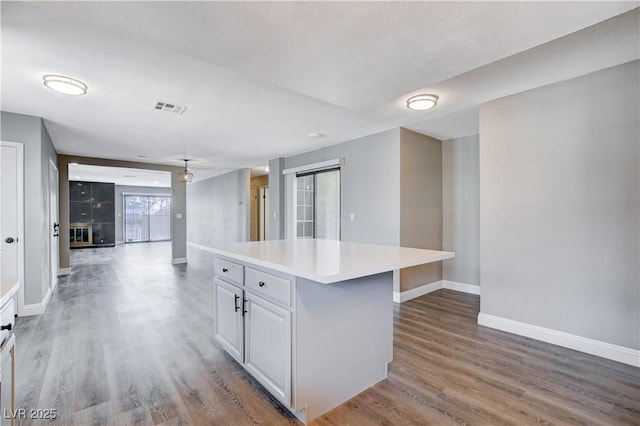 3971 Foxboro Cir, Las Vegas, NV 89121 - kitchen featuring baseboards, wood finished floors, a kitchen island, light countertops, and white cabinets