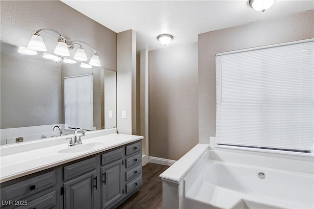 3971 Foxboro Cir, Las Vegas, NV 89121 - full bath featuring a bath, vanity, wood finished floors, a textured wall, and baseboards