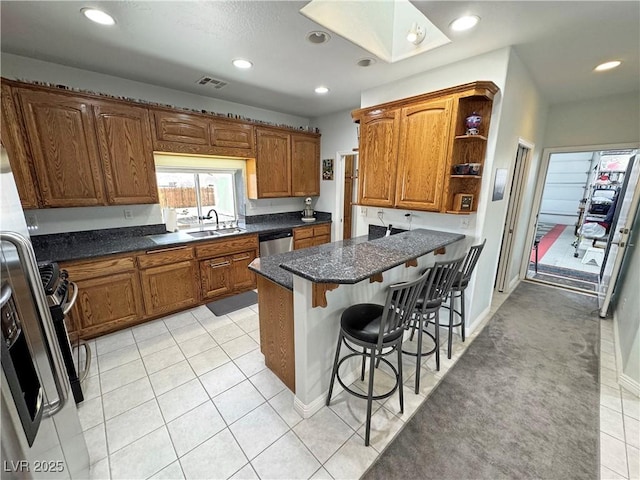 3451 Sagebrush Ave, Pahrump, NV 89048 - kitchen featuring a sink, stainless steel dishwasher, a breakfast bar, brown cabinetry, and a skylight