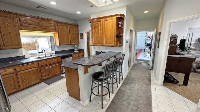 3451 Sagebrush Ave, Pahrump, NV 89048 - kitchen with a sink, stainless steel dishwasher, a kitchen bar, brown cabinets, and light tile patterned floors