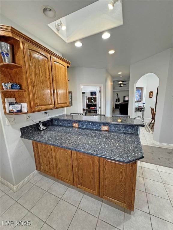 3451 Sagebrush Ave, Pahrump, NV 89048 - kitchen featuring a peninsula, dark stone countertops, open shelves, light tile patterned flooring, and baseboards